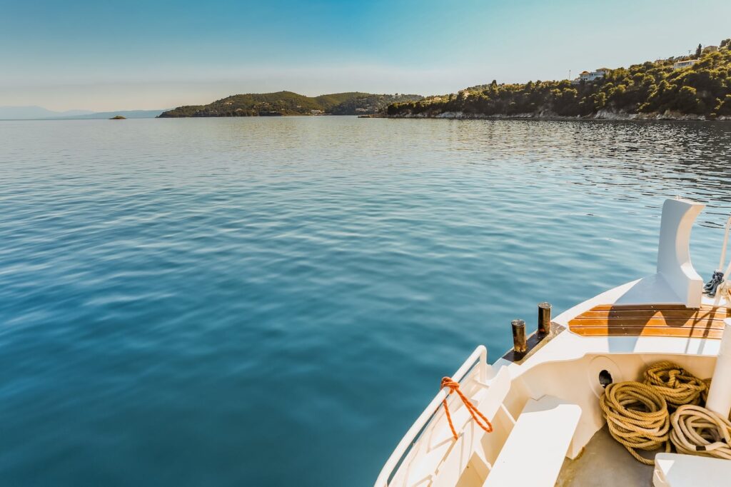wide shot white canoe body water near green island clear blue sky